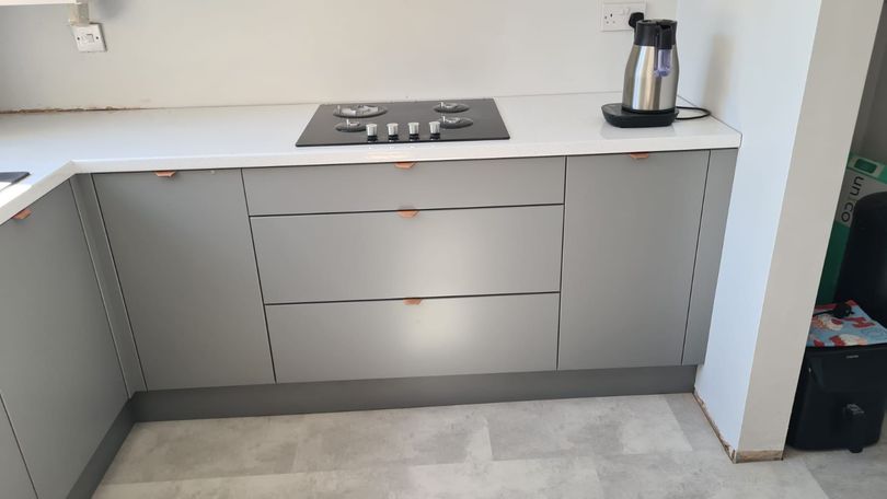 Grey matte kitchen, white shiny ceramic, black stove and kettle