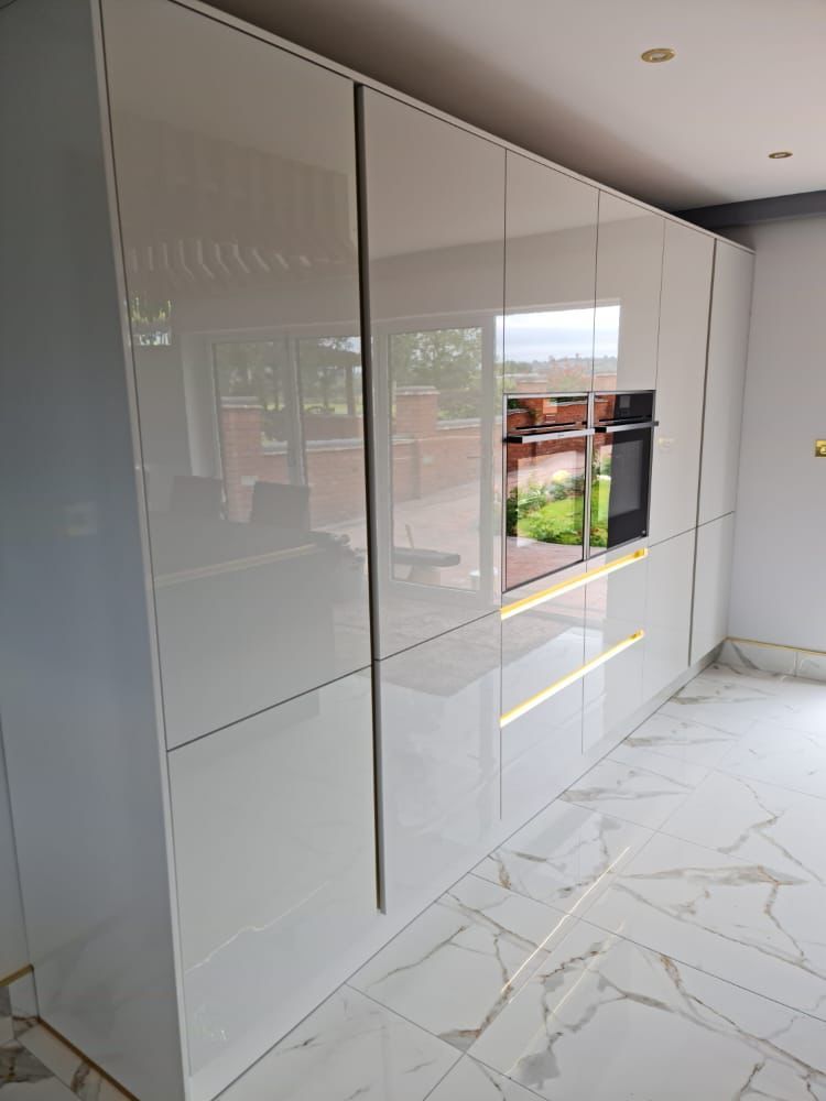 White shiny ceramic kitchen, black oven and gold handle drawers